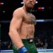 Conor McGregor stands in the octagon wearing green shorts and UFC gloves.
