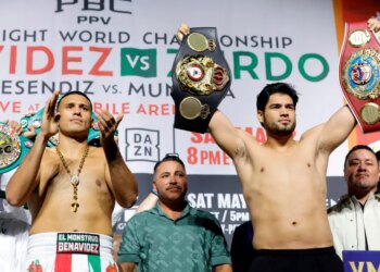 Boxers David Benavidez and Gilberto Ramirez holding championship belts at a weigh-in.