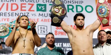 Boxers David Benavidez and Gilberto Ramirez holding championship belts at a weigh-in.