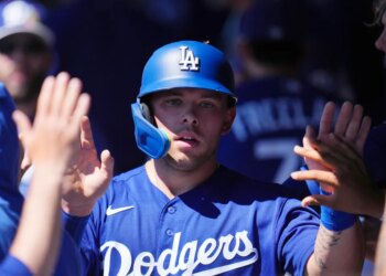 Dalton Rushing in his blue Dodgers uniform and batting helmet high-fives teammates in the dugout.