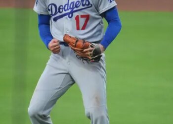 Shohei Ohtani in a Dodgers uniform clenching his fist and yelling.