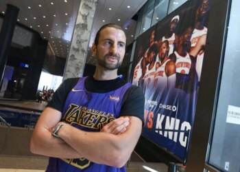 Evan Perlmutter, a former Knicks fan now a Lakers fan, stands with his arms crossed in a Lakers jersey at Madison Square Garden.