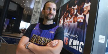 Evan Perlmutter, a former Knicks fan now a Lakers fan, stands with his arms crossed in a Lakers jersey at Madison Square Garden.