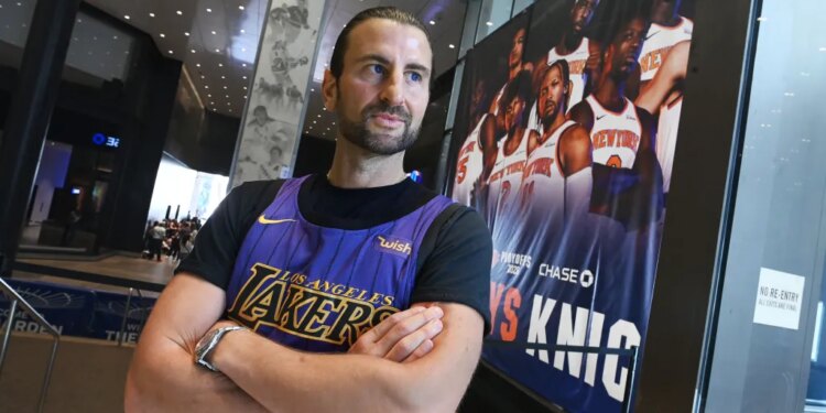 Evan Perlmutter, a former Knicks fan now a Lakers fan, stands with his arms crossed in a Lakers jersey at Madison Square Garden.