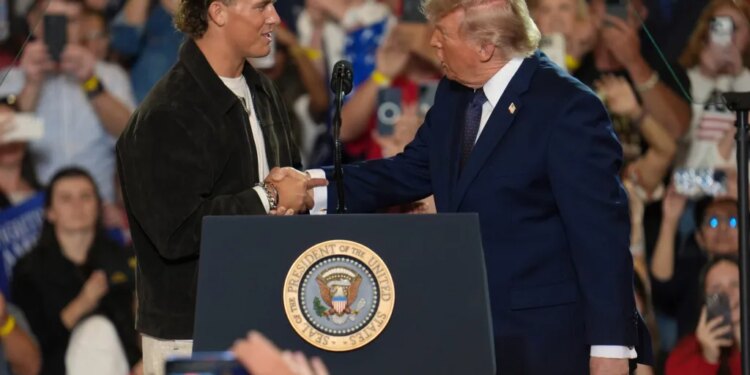 NFL quarterback Jaxson Dart shaking hands with former President Donald Trump at a podium during a Fighting For American Workers event.