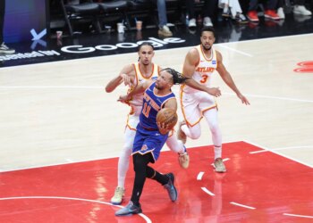 New York Knicks guard Jalen Brunson (11) drives to the basket against two Atlanta Hawks players.