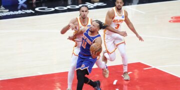 New York Knicks guard Jalen Brunson (11) drives to the basket against two Atlanta Hawks players.