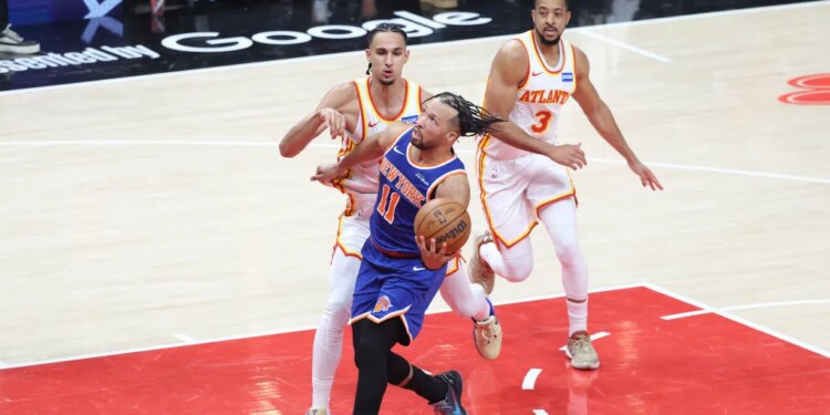 New York Knicks guard Jalen Brunson (11) drives to the basket against two Atlanta Hawks players.