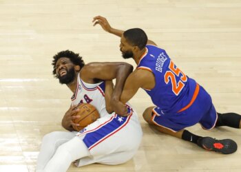 76ers center Joel Embiid (21) grimaces as he and Knicks wing Mikal Bridges (25) fight for control of the ball during Game 4 of the second round on May 10, 2026.