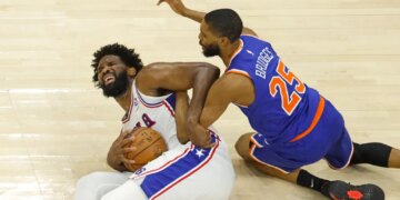 76ers center Joel Embiid (21) grimaces as he and Knicks wing Mikal Bridges (25) fight for control of the ball during Game 4 of the second round on May 10, 2026.