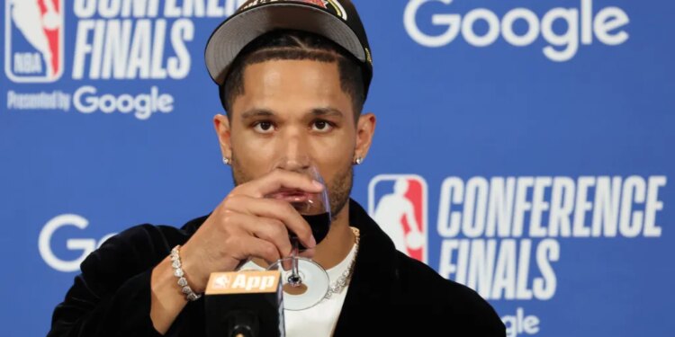 New York Knicks guard Josh Hart drinking from a wine glass at a post-game press conference.