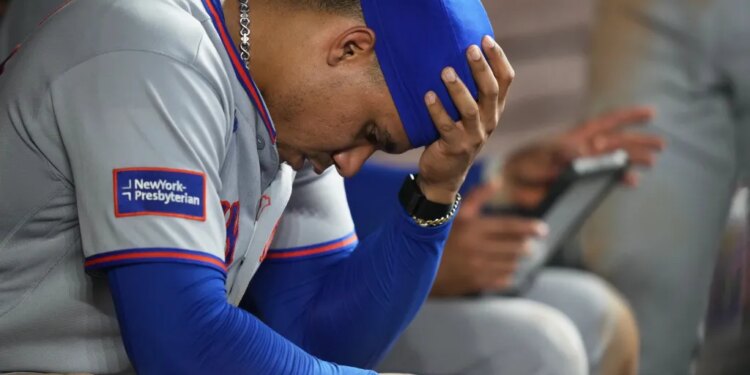 Juan Soto of the New York Mets sitting in the dugout with his head in his hand.
