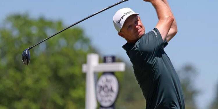Justin Rose follows through on a golf swing, wearing a white "Morgan Stanley" cap and dark green shirt.