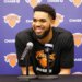 Karl-Anthony Towns smiling at a press conference with two microphones in front of him.