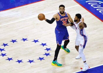 New York Knicks center Karl-Anthony Towns (32) passes the ball as Philadelphia 76ers forward Paul George (8) defends.