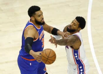 New York Knicks center Karl-Anthony Towns (32) passes the ball as Philadelphia 76ers forward Paul George (8) defends.