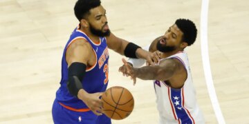 New York Knicks center Karl-Anthony Towns (32) passes the ball as Philadelphia 76ers forward Paul George (8) defends.