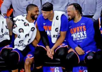 New York Knicks guards Mikal Bridges, Josh Hart, and Jalen Brunson sitting on the bench.