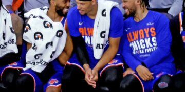 New York Knicks guards Mikal Bridges, Josh Hart, and Jalen Brunson sitting on the bench.