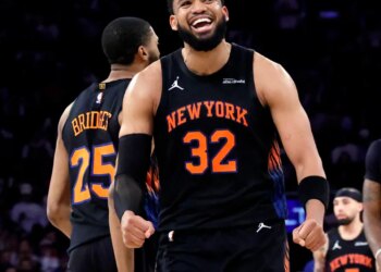 New York Knicks center Karl-Anthony Towns smiles after scoring during a game.