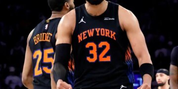 New York Knicks center Karl-Anthony Towns smiles after scoring during a game.