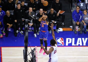New York Knicks guard Jalen Brunson (11) shoots a three-pointer over Philadelphia 76ers center Joel Embiid (21).