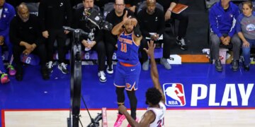 New York Knicks guard Jalen Brunson (11) shoots a three-pointer over Philadelphia 76ers center Joel Embiid (21).