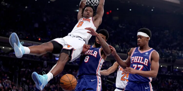New York Knicks forward OG Anunoby #8 slams the ball over Philadelphia 76ers forward Paul George #8 and Philadelphia 76ers guard Vj Edgecombe #77 during the third quarter. 
