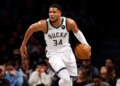 Giannis Antetokounmpo playing basketball in a white Bucks jersey with the number 34.