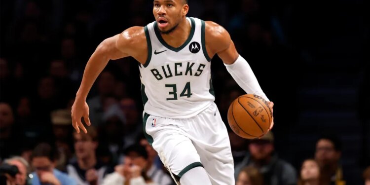 Giannis Antetokounmpo playing basketball in a white Bucks jersey with the number 34.