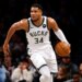 Giannis Antetokounmpo playing basketball in a white Bucks jersey with the number 34.