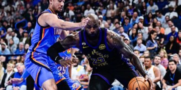 LeBron James drives past Jared McCain in an NBA game.