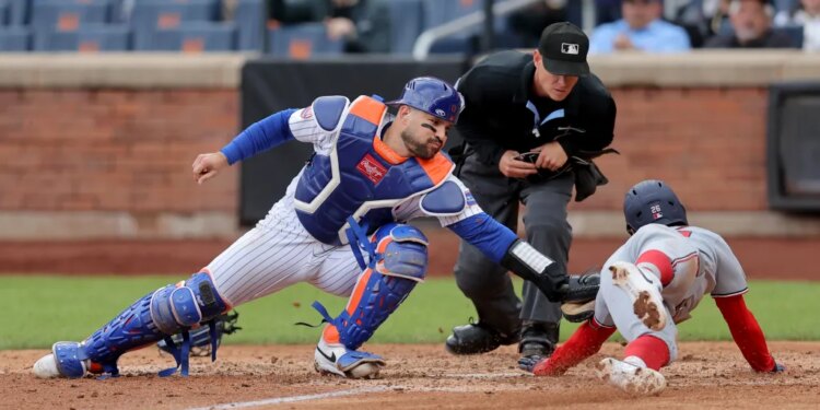 New York Mets catcher Luis Torrens tagging out Washington Nationals second baseman Nasim Nunez at home plate.