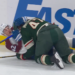Two hockey players, one in maroon and one in green, battling for the puck on the ice.