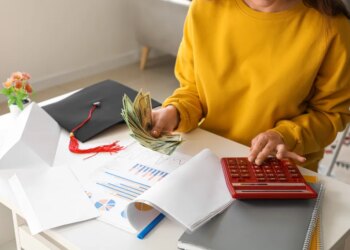 Female student calculating finances and holding dollar banknotes.
