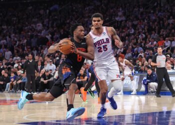 New York Knicks player Og Anunoby driving to the basket with a Philadelphia 76ers player guarding him during an NBA playoffs game.