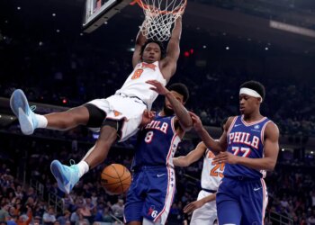 New York Knicks forward Og Anunoby #8 slams the ball over Philadelphia 76ers forward Paul George #8 and Philadelphia 76ers guard Vj Edgecombe #77 during the third quarter.