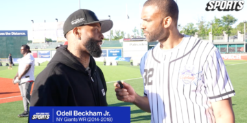 Odell Beckham Jr. being interviewed by a man in a baseball jersey on a sports field.