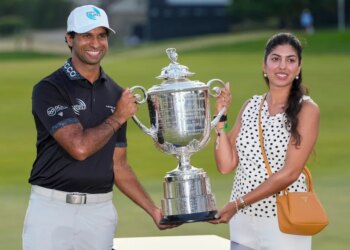 Aaron Rai and Gaurika Bishnoi holding the Wanamaker Trophy after Rai's PGA Championship golf tournament win.