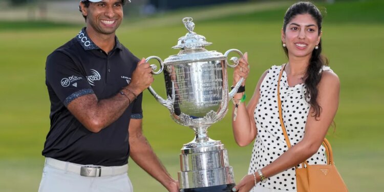 Aaron Rai and Gaurika Bishnoi holding the Wanamaker Trophy after Rai's PGA Championship golf tournament win.