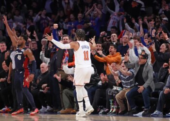 New York Knicks guard Jalen Brunson #11 celebrating a 3-point shot against the Cleveland Cavaliers, with fans cheering in the background.