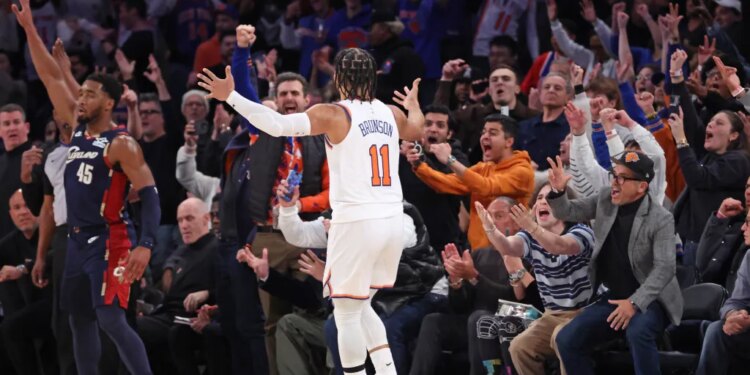 New York Knicks guard Jalen Brunson #11 celebrating a 3-point shot against the Cleveland Cavaliers, with fans cheering in the background.