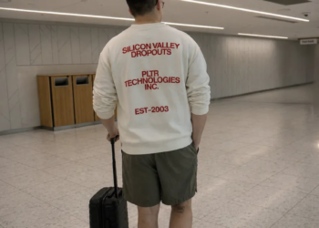 A man in a white Palantir sweatshirt that says “Silicon Valley dropouts.”