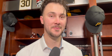 Man being interviewed in a locker room with a "30" sign in the background.