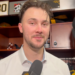 Man being interviewed in a locker room with a "30" sign in the background.