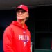 Don Mattingly in a Phillies baseball cap and red hoodie, standing in a dugout.