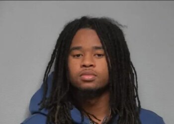 Mugshot of a young man with long dreadlocks wearing a blue hoodie.