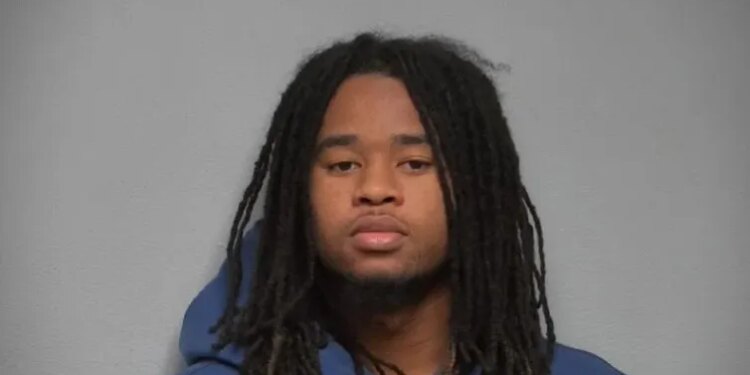 Mugshot of a young man with long dreadlocks wearing a blue hoodie.