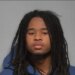 Mugshot of a young man with long dreadlocks wearing a blue hoodie.