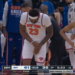 Mitchell Robinson, in a white New York Knicks jersey, clutches his right hand in pain.